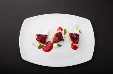 Beyaz tabakta servis edilen farklı meyveli tartlar.