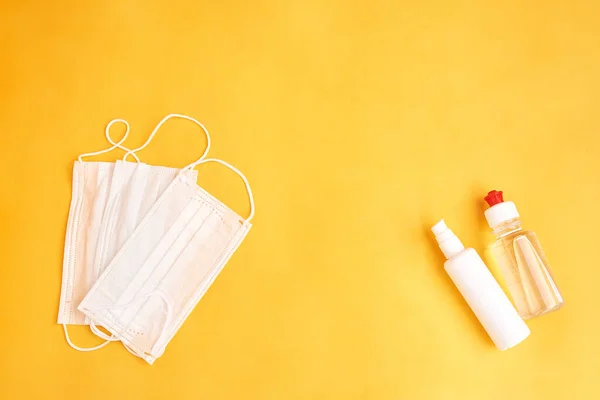 Medical protective mask and antiseptic bottles isolated on yellow background. Healthcare medical Coronavirus quarantine — Stock Photo, Image