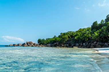 Güzel sahil. Anse Coco plajında ünlü granit kayalıkları olan güzel tropikal kumlu sahil manzarası, La Digue Adası, Seyşeller. Tatil ve tatil konsepti. Arka planda tropik plaj Mavi gökyüzü