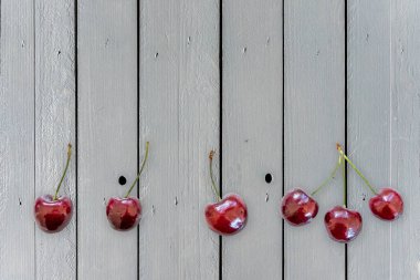 Gri ahşap masa üzerinde tatlı kirazlı düz kompozisyon. Metin için alanı olan panoramik manzara.