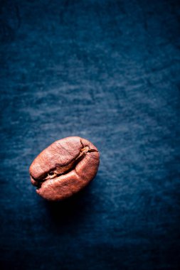 Koyu bir arka planda, izole edilmiş kahve çekirdeğinin aşırı yakın çekimi. Metin için kopyalama alanı olan portre biçimi