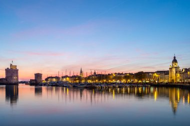 Gün batımında meşhur eski kuleleriyle La Rochelle 'in eski limanının panoramik manzarası. Güzel pastel renkli gökyüzü