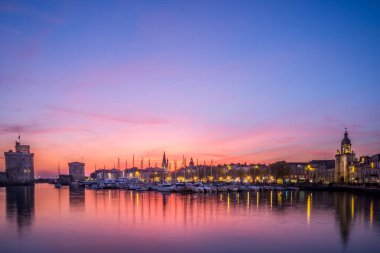 Gün batımında meşhur eski kuleleriyle La Rochelle 'in eski limanının panoramik manzarası. Güzel turuncu gökyüzü