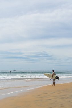 Sahilde sörfçü, güneşli bir gün ve bulutlu bir gökyüzü, Arugam Körfezi, Sri Lanka
