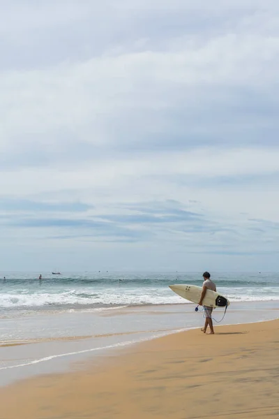 Sahilde sörfçü, güneşli bir gün ve bulutlu bir gökyüzü, Arugam Körfezi, Sri Lanka