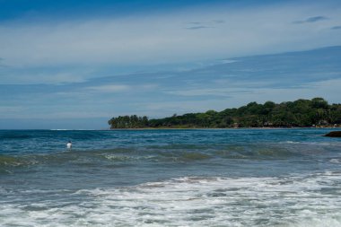 Denizde sörfçü, turkuaz su, mavi gökyüzü. Arugam Körfezi, Sri Lanka. Portre biçimi