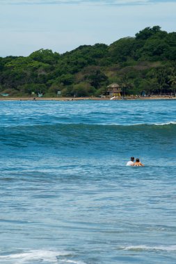 Denizde sörfçü, arka planda palmiye ağaçları, mavi gökyüzü. Arugam Körfezi, Sri Lanka. Portre biçimi