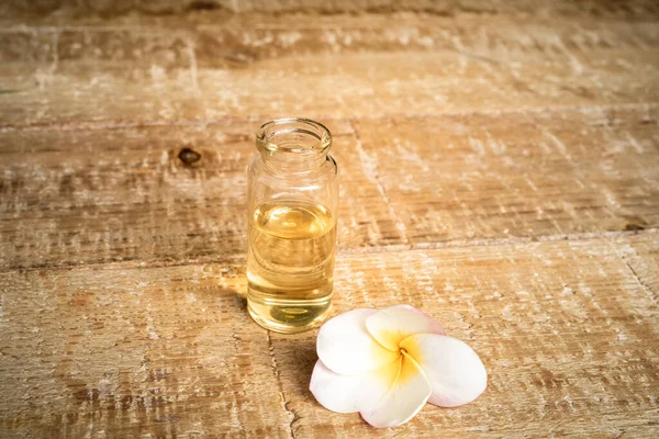 Close Essential Oil Small Glass Bottle Frangipani Flowers Wooden Background — Stock Photo, Image