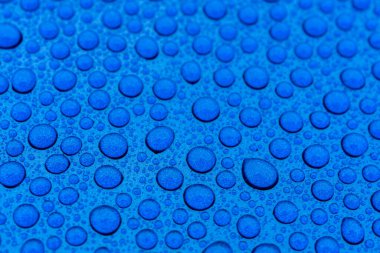 Seramik kaplamadan sonra mavi bir arabanın kaputuna su damlaları yakın çekim