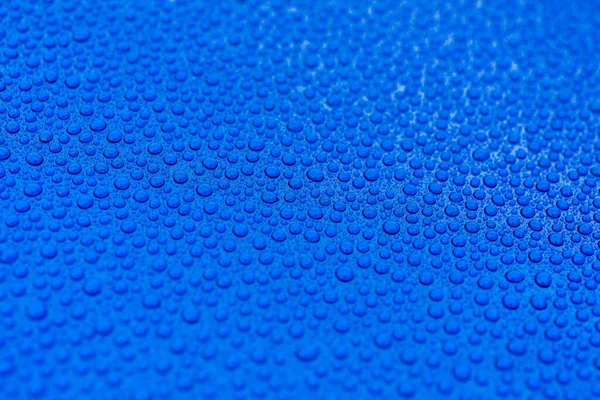 Seramik kaplamadan sonra mavi bir arabanın kaputuna su damlaları yakın çekim