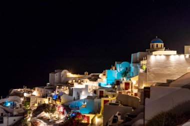 Santorini adasındaki Yunan köyü Oia 'da gece çöküyor. Tipik ortodoks kilisesi. Yuvarlak ve mavi çatılı.