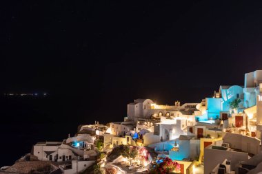 Santorini adasındaki Yunan köyü Oia 'da gece çöküyor. Tipik bir ortodoks kilisesi köyü asıyor. Yıldızlı güzel gökyüzü