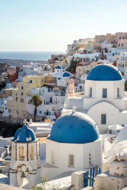 Santorini manzarası, tipik mavi kubbe kilisesi, deniz ve beyaz evler.