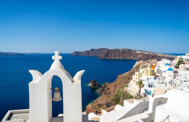 Santorini Kalderası 'nın panoramik manzarası Oia kasabası ve ünlü eski beyaz kule çanları ve ortodoks kiliselerinin mavi kubbeleri.