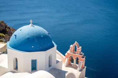 Santorini 'nin tipik mavi kubbe kilisesi, deniz ve santorini kalderası manzarası.