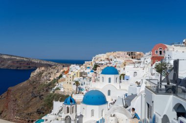 Santorini manzarası, tipik mavi kubbe kilisesi, eski badanalı evler ve kaldera. Güneşli bir günde Yunan manzarası