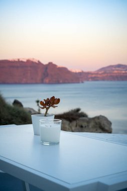 Mum ve bitki süslemesi beyaz bir masada. Oia, Santorini Adası, Yunanistan. Caldera 'da günbatımının güzel renkleri. Portre biçimi