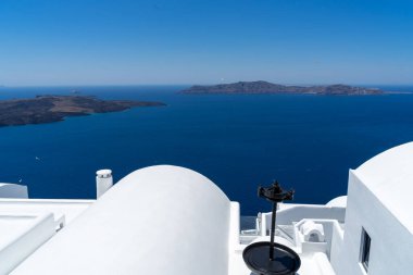 Yunanistan 'ın Santorini adasındaki bir evin beyaz çatısında dekorasyon için kullanılan eski metalik bir alet. Mavi Akdeniz ve arka planda Santorini kalderası. Portre biçimi