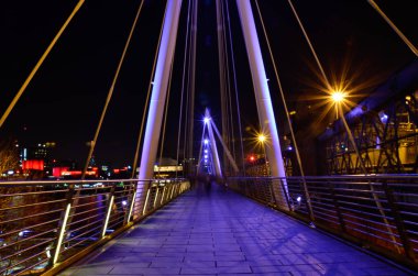 Londra 'da bir köprüde yürüyen insanların uzun pozu.