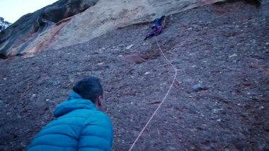 Arkadaşlar doğada kırmızı kayalara tırmanıyor. Yüksek kalite 4k görüntü