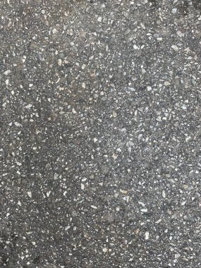 Sert asfalt yüzeyi. Açık gri yol dokusu. Tahıllı asfalt üst görüş. Terrazzo tekniği. Kaynamış taş parçaları. Makro arka plan..