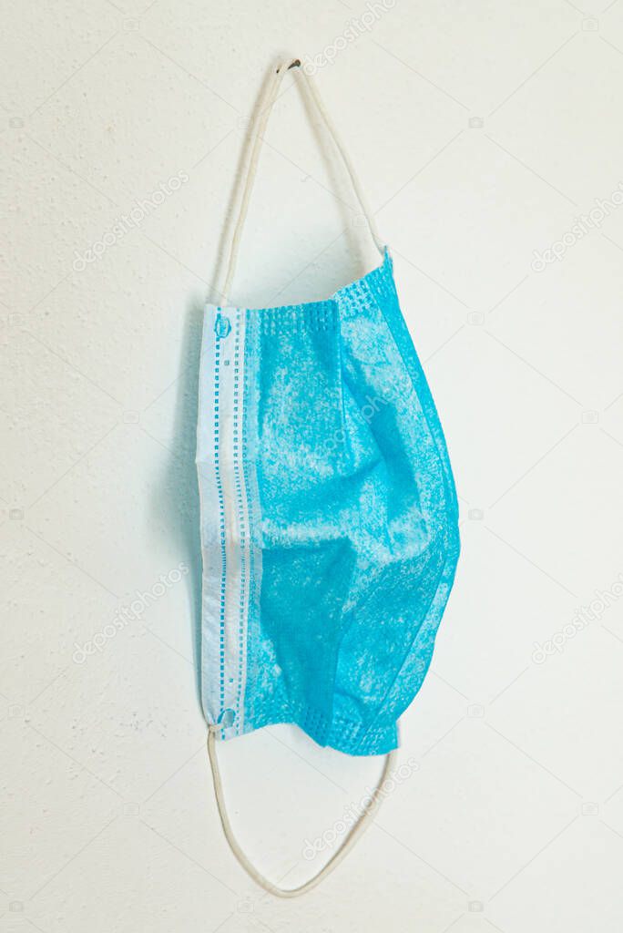 Blue surgical masks, hanging on a white wall