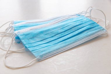 Mavi cerrahi maskeler, beyaz yüzeye yerleştirilmiş.