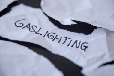 Word Gaslighting, written on white torn paper clipart
