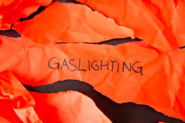 Sözcük Gaslighting, yırtık kırmızı kağıda yazılmış.