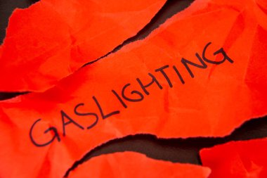 Sözcük Gaslighting, yırtık kırmızı kağıda yazılmış.