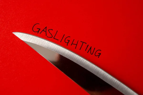 Sözcük Gaslighting, kırmızı kağıda yazılmış, yanında bıçak var.