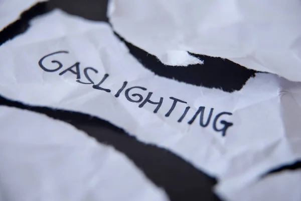 Sözcük Gaslighting, beyaz yırtık kağıda yazılmış.