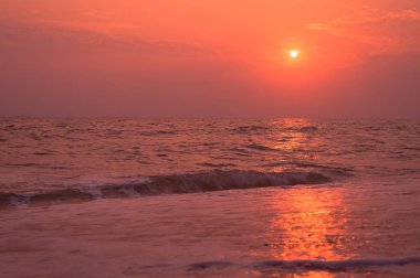 Sahilde yaz günbatımı manzarası. Parlak günbatımı manzarası ve üzerinde güneş yansıması olan turuncu gökyüzü..