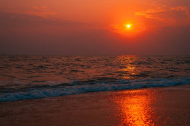 Sahilde yaz günbatımı manzarası. Parlak günbatımı manzarası ve üzerinde güneş yansıması olan turuncu gökyüzü..