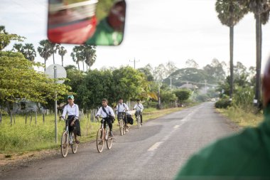 CAMBODIA, KAMPONG THOM - NOVEMBER, 2017: school childern on bicycle at a road near the city centre of Kampong Thom of Cambodia clipart