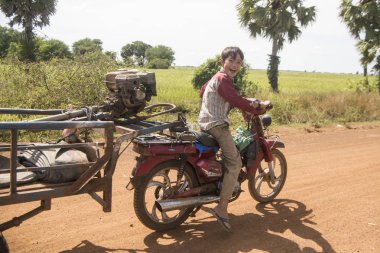 Kamboçya, Kampong Thom - Kasım, 2017: Çiftçi bir alan ve peyzaj Kamboçya Kampong Thom şehir yakınındaki bir motosiklet ile
