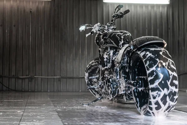 Czarny motocykl w piance mydlanej w myjni samochodowej — Zdjęcie stockowe