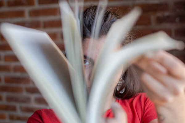 Молодая женщина с книгой в руках проходит через простыни, глядя через них