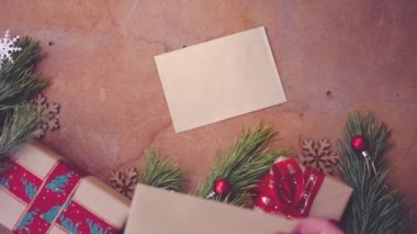 Mutlu Noel kavramı Çam ağaç dalları, hediye kutuları ve boş kartı masanın üzerine koyarak el ile