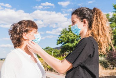 Yeni normal. Anne ve kızı kendilerini koronavirüse karşı koruyorlar. Anne kızını salgından korumak için maske takıyor. Coronavirus cihazları. Güvenlik ve salgın konsepti
