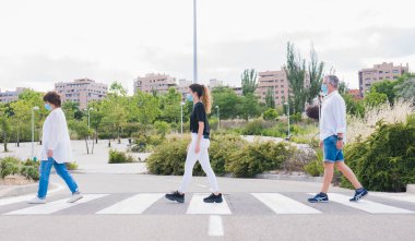Yeni normal. Sosyal mesafede insan hayatı. İnsanlar yaya geçidinden güvenli mesafede yürürken maske takarak geçiyorlar. Güvenlik ve salgın konsepti. Coronavirus. Sosyal uzaklık.