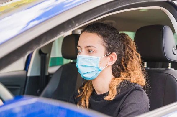 Yeni normal. Tıbbi maskeli bir kadın sürücü bir yolcuyla araba kullanıyor. Sağlık koruması. Arabadaki aile maske güvenliği ve salgın hastalık konseptiyle korunuyor. Coronavirus. Sosyal uzaklık.