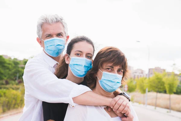 Yeni normal. Maskeli aile kucaklaşması. Aile üyeleri birbirlerine koruyucu maskelerle sarılırlar. Koronavirüse karşı maskeli bir aile. Güvenlik ve salgın konsepti. Coronavirus. Sosyal uzaklık.