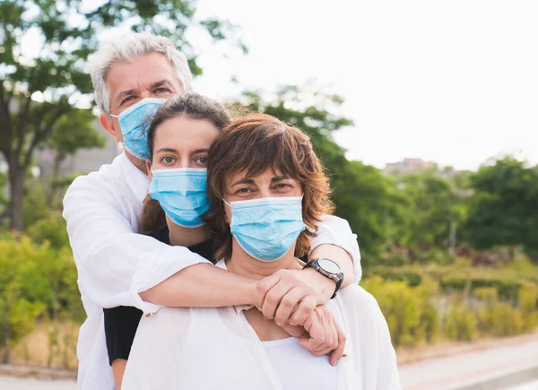 New normal. Masked family hugs. Members of a family hug each other with protective masks. Family protected with masks against coronavirus. Safety and pandemic concept. Coronavirus. Social distance.