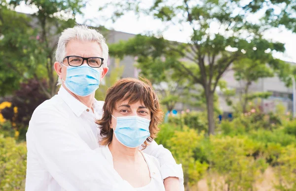 Yeni normal. Aile üyeleri sarılıyor. Koronavirüse karşı korunan karı koca kucaklaşması. Güvenlik ve salgın konsepti. Coronavirus. Sosyal mesafe. Evlilik maskelerle korunur..