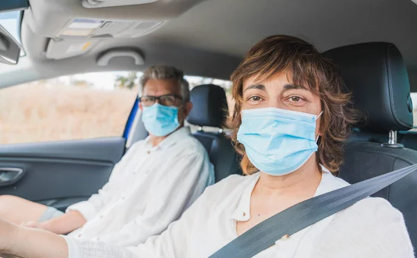 Yeni normal. Tıbbi maskeli bir kadın sürücü bir yolcuyla araba kullanıyor. Sağlık koruması. Arabadaki aile maske güvenliği ve salgın hastalık konseptiyle korunuyor. Coronavirus. Sosyal uzaklık.