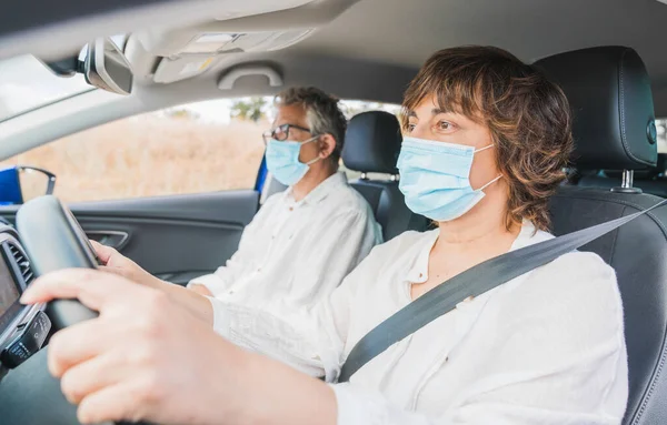 Yeni normal. Tıbbi maskeli bir kadın sürücü bir yolcuyla araba kullanıyor. Sağlık koruması. Arabadaki aile maske güvenliği ve salgın hastalık konseptiyle korunuyor. Coronavirus. Sosyal uzaklık.