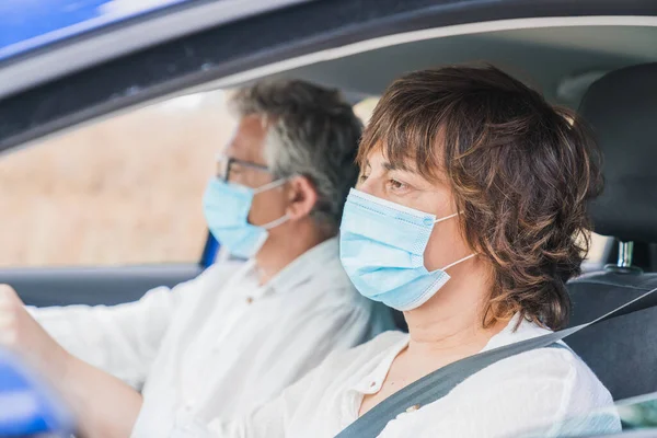 New normal. Female driver with a medical face mask driving a car with a passenger. Health protection. Family in the car protected by a mask safety and pandemic concept. Coronavirus. Social distance.