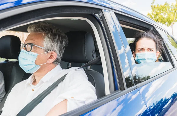 New normal. Driver with a medical face mask driving a car with a passenger. Health protection. Family in the car protected by a mask safety and pandemic concept. Coronavirus devices. Social distance.