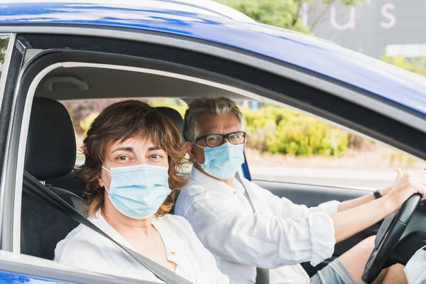 Yeni normal. Tıbbi maskeli bir sürücü bir yolcuyla araba kullanıyor. Sağlık koruması. Arabadaki aile maske güvenliği ve salgın hastalık konseptiyle korunuyor. Coronavirus cihazları. Sosyal uzaklık.